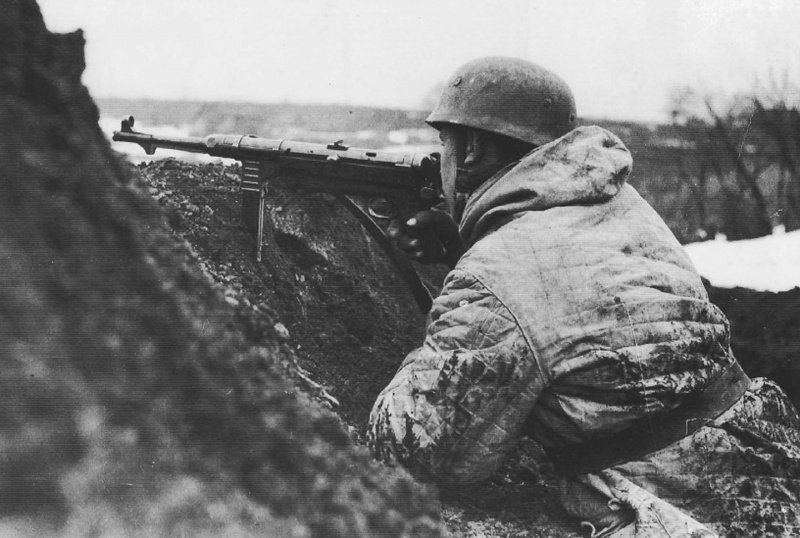 Немецкий парашутист, вооруженный пистолетом-пулеметом MP-40, в окопе. Восточный фронт 1942—1943 гг.